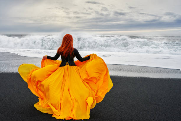 fashion model with flying yellow dress on beach in Iceland in cold day.photo taken on Reynisfjara beach, Iceland.