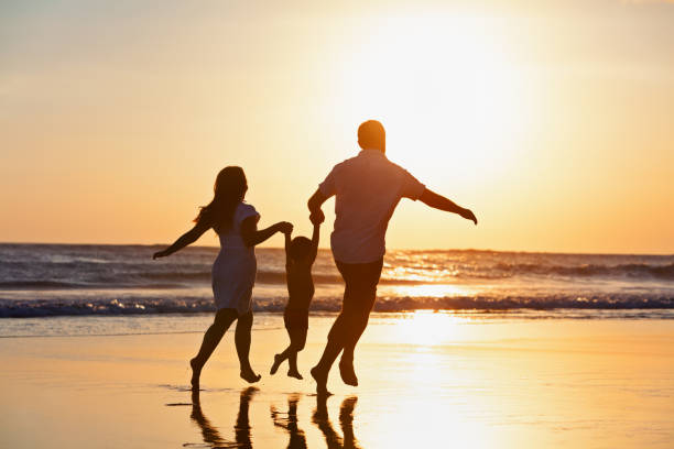 glückliche familie läuft am strand von sonnenuntergang - hochspringen fotos stock-fotos und bilder