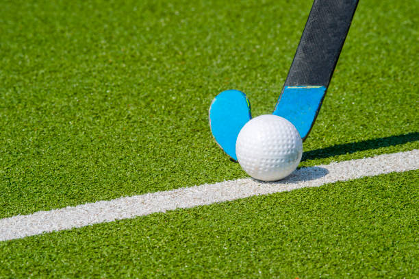 istock Field hockey stick and ball on green grass 1145984809