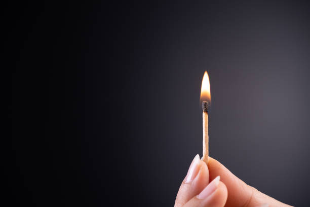 istock Close up woman hand holding a burning match. 1145985202