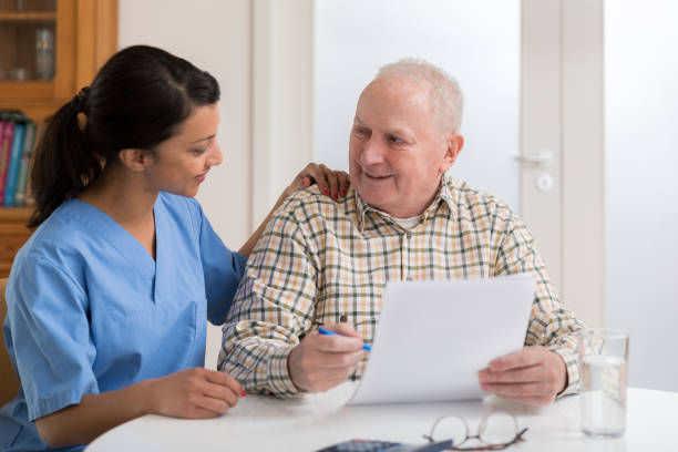 istock Home caregiver and elderly man reading paperwork 1145988579