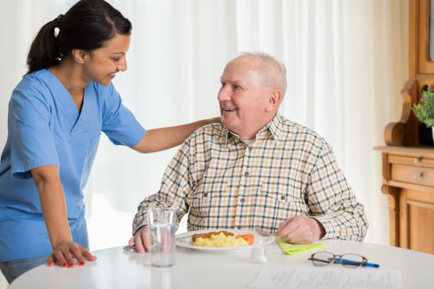 istock Home caregiver giving senior man lunch 1145988581