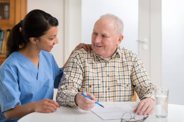 istock Home caregiver and elderly man reading paperwork 1145988785