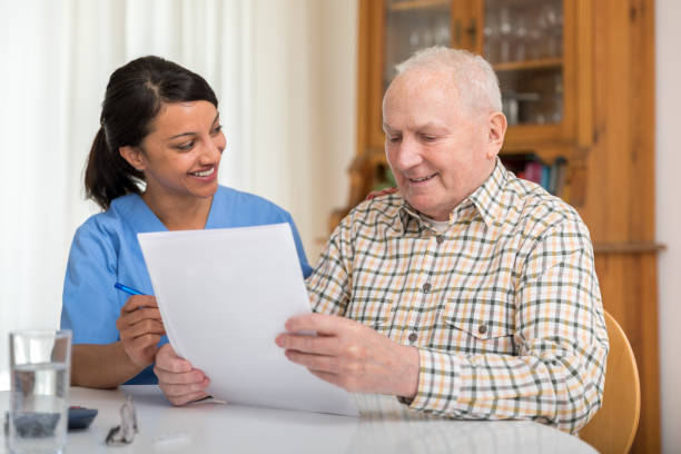 istock Home caregiver and elderly man reading paperwork 1145988982