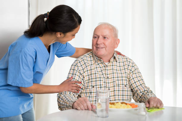 istock Home caregiver giving senior man lunch 1145989298