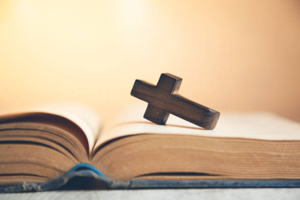istock wooden cross on the  book 1145992419