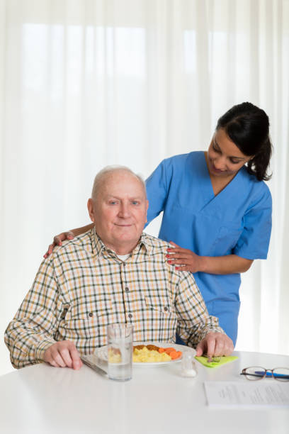 istock Home caregiver giving senior man lunch 1145992725