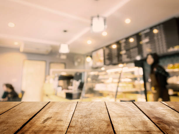 istock Perspective wood table top texture white blur modern interior retail shop business background. Abstract window light bokeh effect of coffeeshop counter concept for blurry office break dessert breakfast, defocus cafe restaurant mockup product montage 1145992727