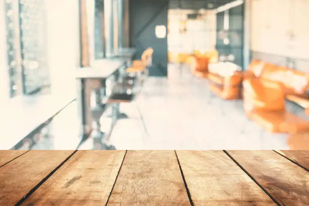 Perspective wood table top texture white blur modern interior retail shop business background. Abstract window light bokeh effect of coffeeshop counter concept for blurry office break dessert breakfast, defocus cafe restaurant mockup product montage