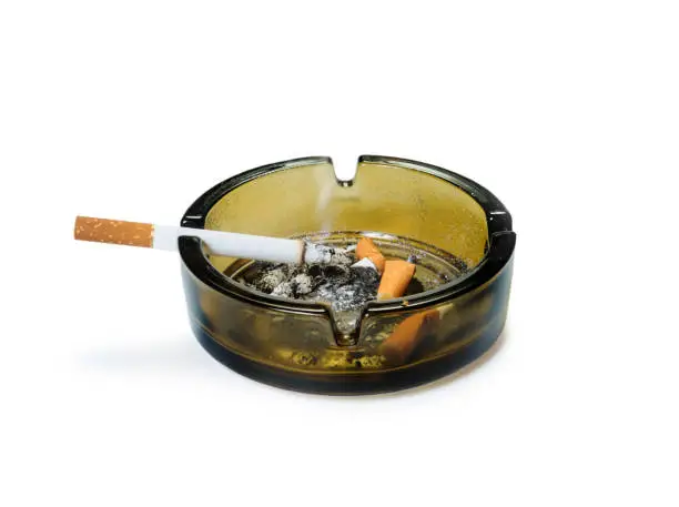 Ashtray with smoking cigarettes on it and butts inside. Isolated with clipping path