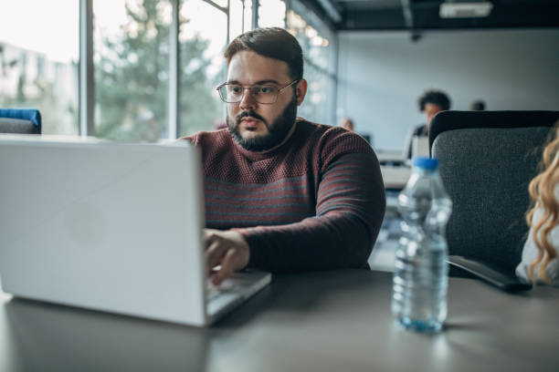 istock Overweight man working on laptop in big modern office 1145996099