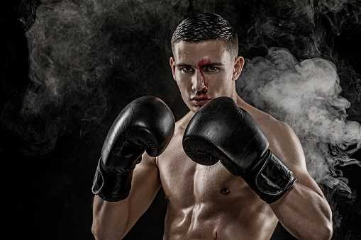 Young adult mixed race Man muscular teenage fighter shadow boxing in a smoke filled studio shoot