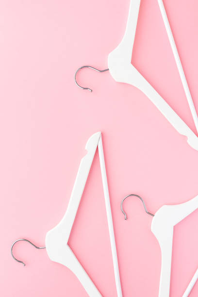 istock White hangers on pastel pink background 1146002683