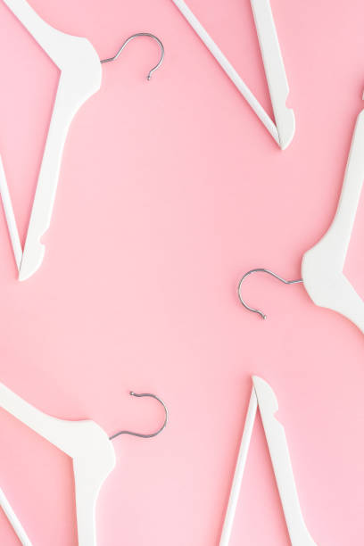 istock White hangers on pastel pink background 1146002906