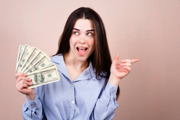 istock rich young woman with money pointing on free space 1146002955