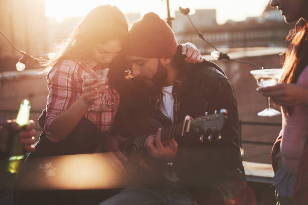 istock Drunk enough to give a hug. Friends have fun at rooftop party with decorative colored light bulbs 1146005775