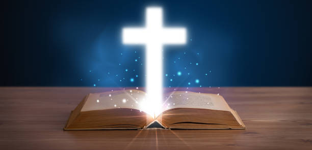 istock Open holy bible with glowing cross in the middle 1146007001