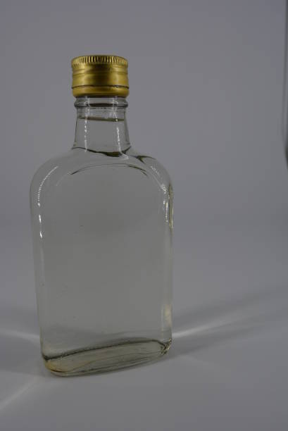 istock Alcoholic beverage, water, vodka, grappa, moonshine in a glass bottle and a gold cap on a white light background with the promise. 1146007870