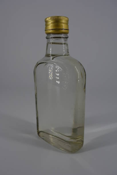 istock Alcoholic beverage, water, vodka, grappa, moonshine in a glass bottle and a gold cap on a white light background with the promise. 1146007879