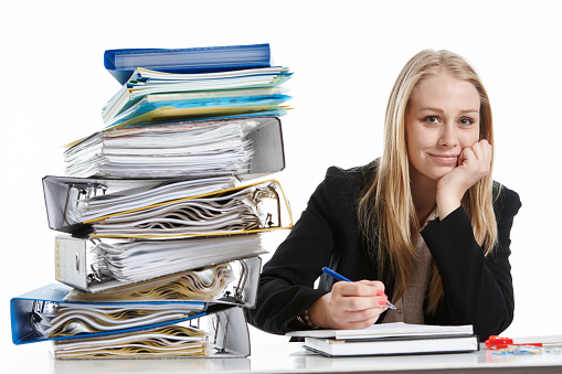 A lovely blonde office worker smiles, confident that she can handle the huge stack of work files awaiting her attention.