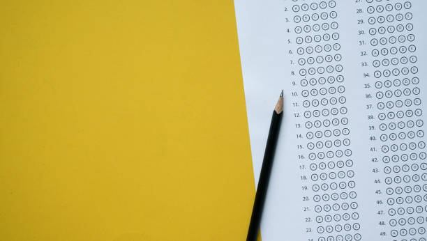 da vicino vista dall'alto della matita nera sopra il foglio di risposte dell'esame con scelta multipla su sfondo giallo per la giornata mondiale dell'alfabetizzazione e il concetto di educazione - paper match foto e immagini stock