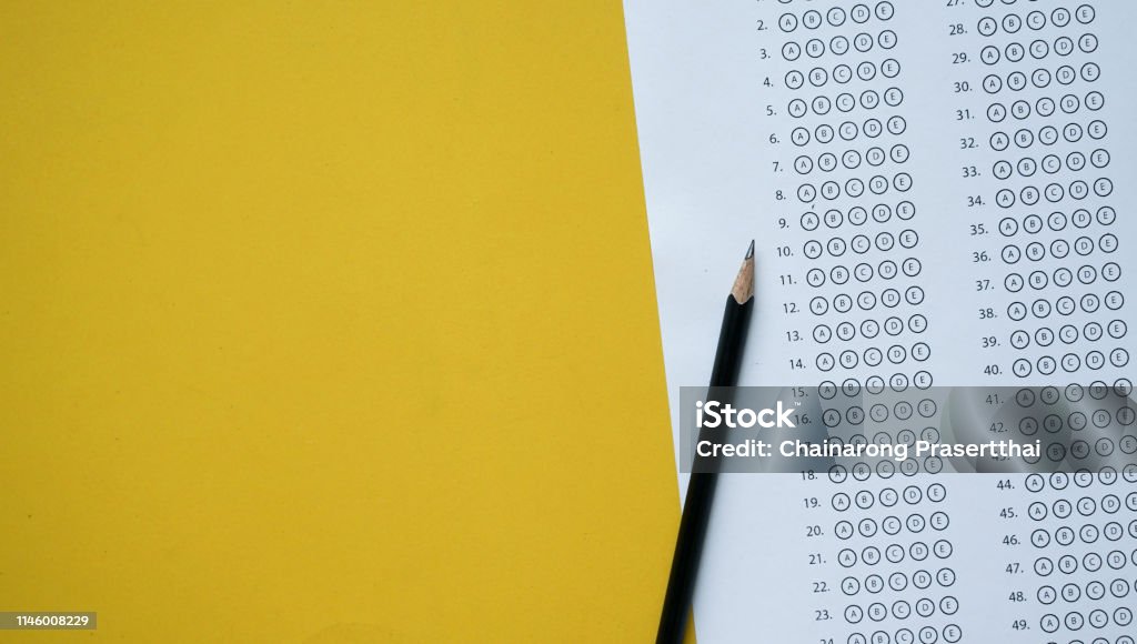 close up top view of black pencil over exam answer sheet paper with multiple choice on yellow background for world literacy day and education concept Educational Exam Stock Photo