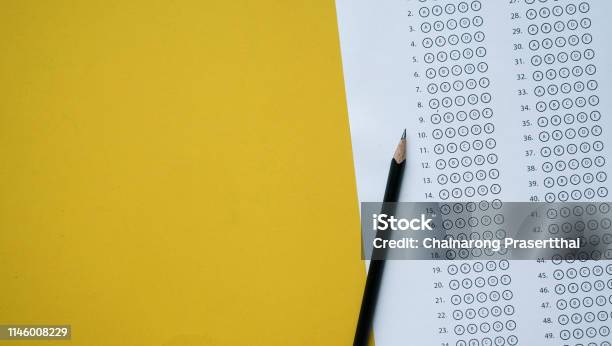 Close Up Top View Of Black Pencil Over Exam Answer Sheet Paper With Multiple Choice On Yellow Background For World Literacy Day And Education Concept Stock Photo - Download Image Now