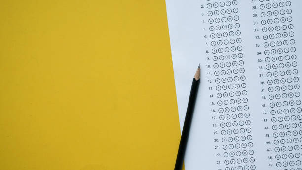 närbild topp bild av svart penna över tentamen svars blad papper med flera val på gul bakgrund för världs kunskap dag och utbildning koncept - study school bildbanksfoton och bilder