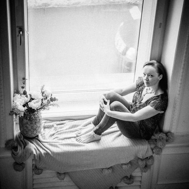 istock A woman is sitting on the windowsill and looking at camera 1146014351