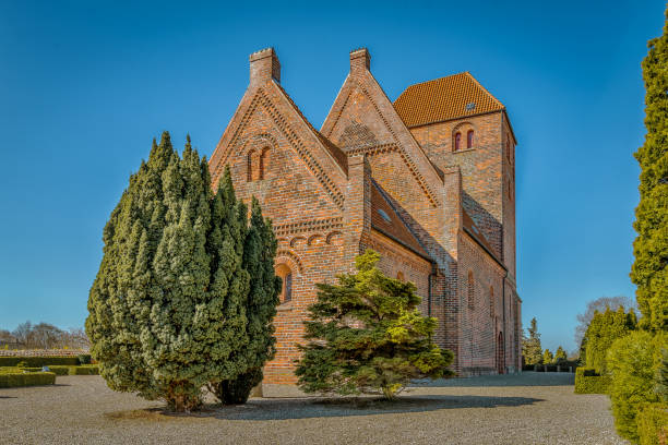 istock Medieval danish brick church with blue sky and green trees 1146014706
