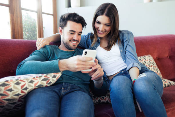 istock Lovely young couple using they mobile phone while sitting on sofa at home. 1146017631