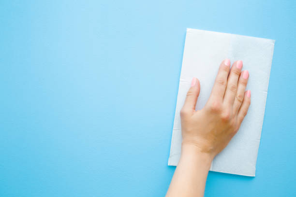 Woman's hand wiping pastel blue desk with white paper napkin. General or regular cleanup. Close up. Empty place for text or logo. Top view. Woman's hand wiping pastel blue desk with white paper napkin. General or regular cleanup. Close up. Empty place for text or logo. Top view. rubbing photos stock pictures, royalty-free photos & images