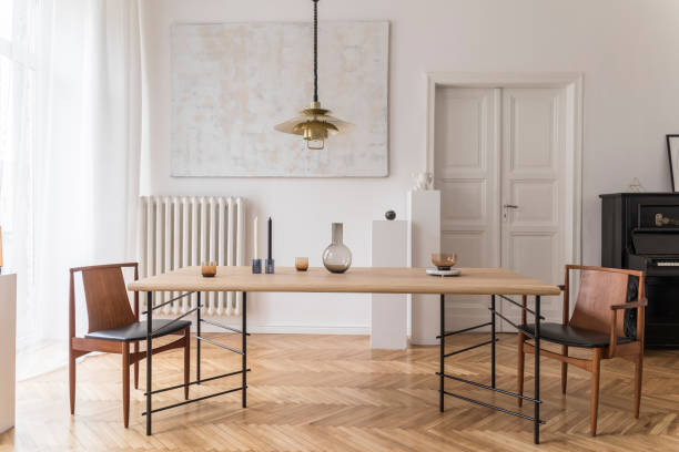 istock Eclectic and elegant dining room interior with design sharing table, chairs, gold pedant lamp, abstract paintings, piano and stylish accessories. Minimalistic decor. Brown wooden parquet. Real photo. 1146020410