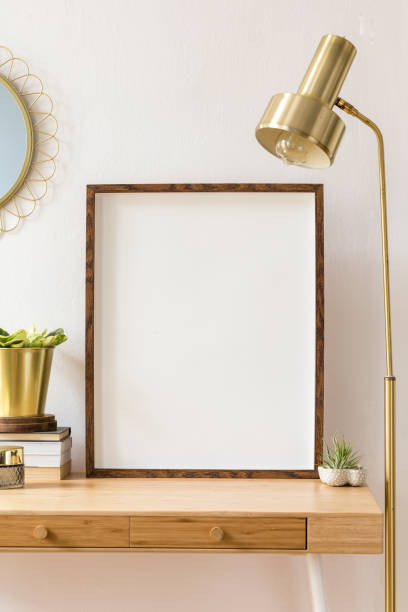 istock Modern scanidnavian interior with mock up photo frame, design office accessories and plants on the wooden desk. Beautiful mirror on the white wall. Creative desk of home decor. Warm and sunny room. 1146021127