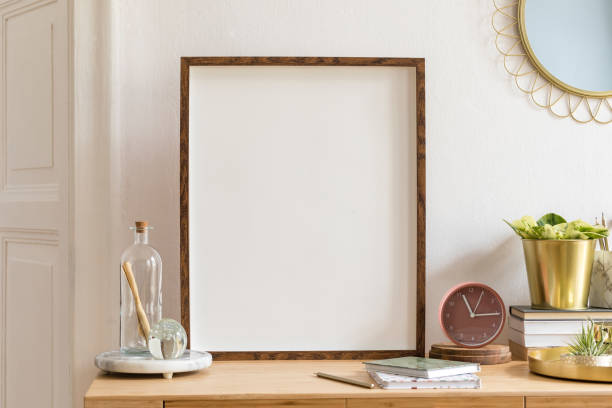 istock Modern scanidnavian interior with mock up photo frame, design office accessories and plants on the wooden desk. Beautiful mirror on the white wall. Creative desk of home decor. Warm and sunny room. 1146021128