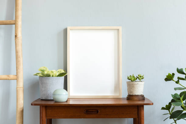 istock Stylish scandinavian room with design retro small table, mock up poster frame, elegant accessories, wooden ladder and beautiful plants in cement pots. Minimalistic home decor. Gray background wall. 1146021426