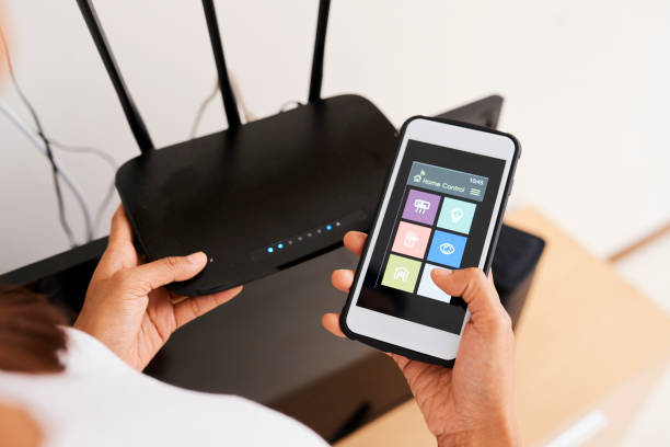 Connecting online smart home system with wi-fi router Close-up of woman using smart home system on her mobile phone and connecting it with wi-fi router router stock pictures, royalty-free photos & images