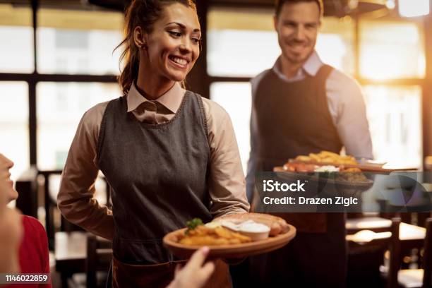 Happy Waiters Serving Food To Their Guests In A Restaurant Stock Photo - Download Image Now
