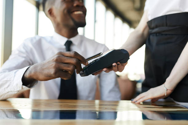 istock Close-up of smiling black businessman sitting at table and using nfc technology for mobile payment in restaurant 1146022893