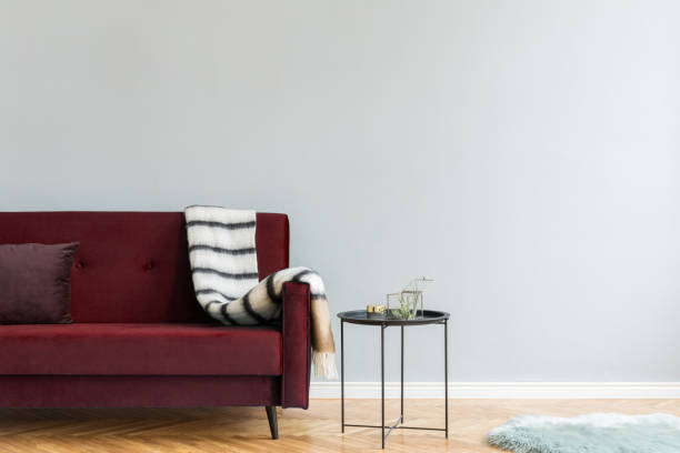 istock Minimalistic and luxury grey home interior with green velvet design sofa, black coffe table with airplant, carpet and elegant blanket. Copy space for inscription, mock up poster. Brown wooden parquet. 1146023261