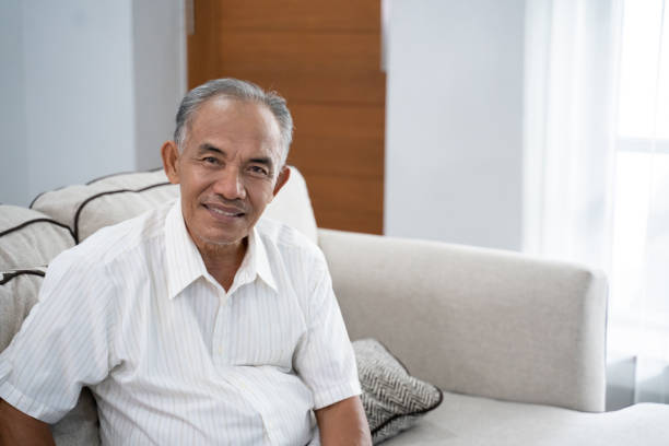 istock Asian old man sitting on the sofa with a smile looking at the camera 1146023910