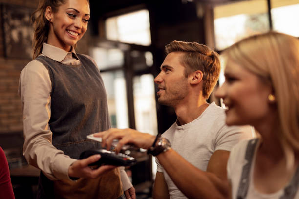 istock Young man making contactless payment via smart phone in a cafe. 1146024421
