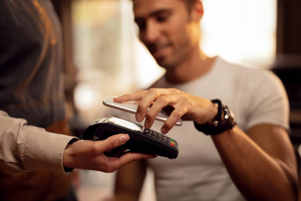 Close up of man making contactless payment in a cafe.