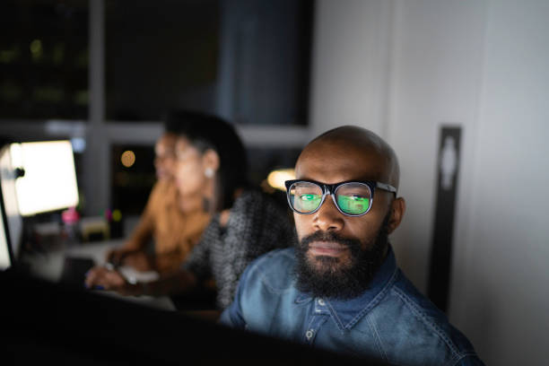 Portrait of businessman working late in the office Portrait of businessman working late in the office group of people men mature adult serious stock pictures, royalty-free photos & images