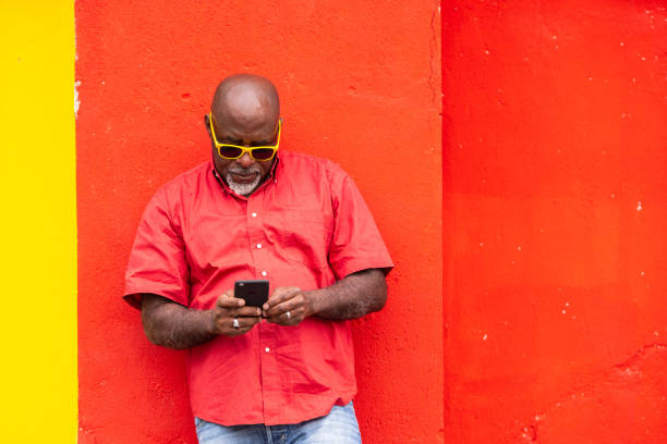 Mature afro man on colorful background using smartphone