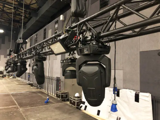 Photo of Spot lighting equipment is clamped on a truss for lifting. Installation of professional stage light equipment for a concert.