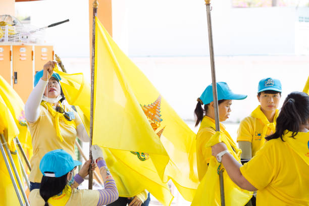 Capture of Thai women with royal thai flags seen in Lampang. Women are volunteers and are preparing flags for streets for coronation day of king Rama X in May 2019.