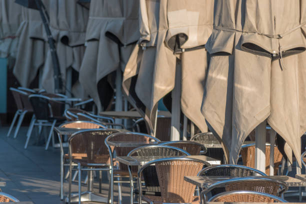 istock Empty tables with umbrelas in restaurant on the street during sunrise. 1146033055