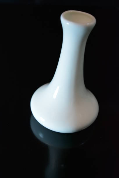 istock On a black glossy background is a white ceramic vase with reflection. 1146033566