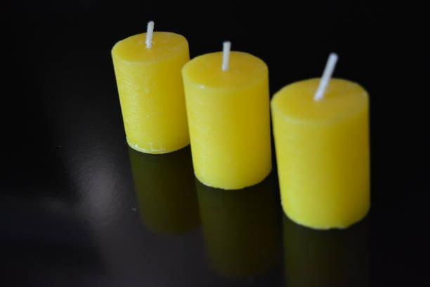 istock On black glossy background there are beautiful three round yellow candles with reflection. 1146036290